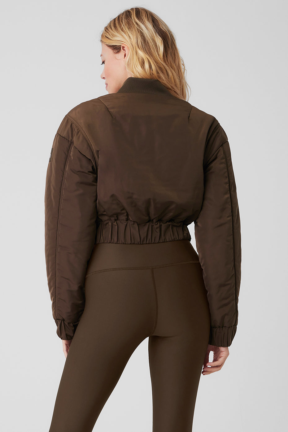 Cropped Break Line Bomber Jacket featuring memory woven fabric, ribbed cuffs, and waistband, worn with leggings.