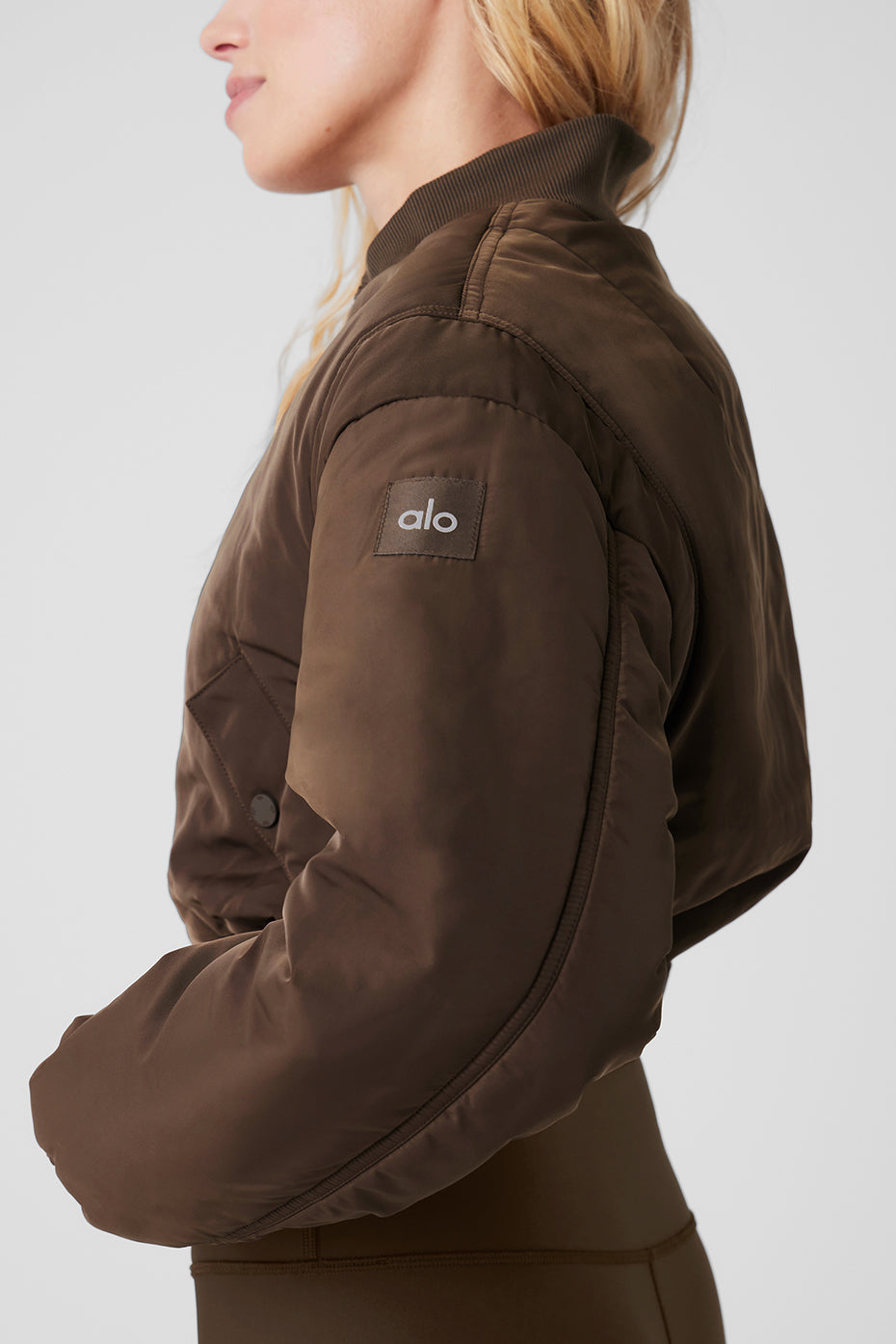 Cropped Break Line Bomber Jacket in brown featuring snap pockets and ribbed collar, perfect for studio or casual wear.