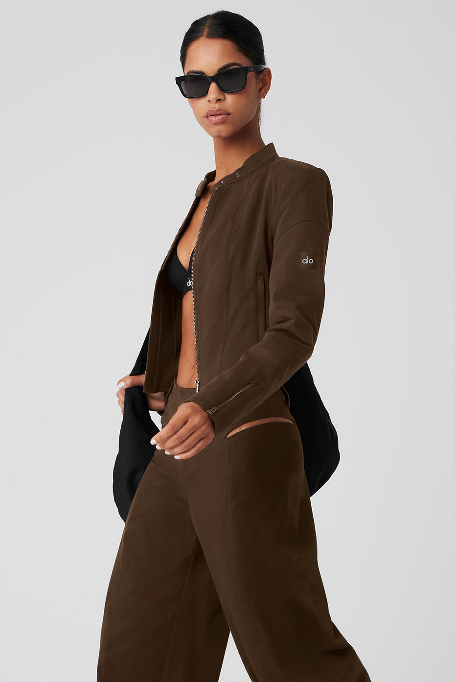 Model wearing a cropped Full Throttle Moto Jacket in brown with a zipper, styled with a bikini top and sporty pants.