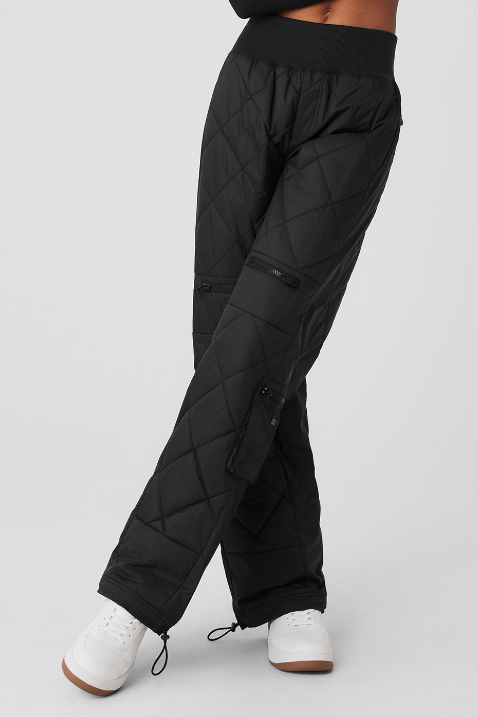 High-waist snowrider puffer pant in black with quilted finish, ribbed waistband, and zippered pockets.