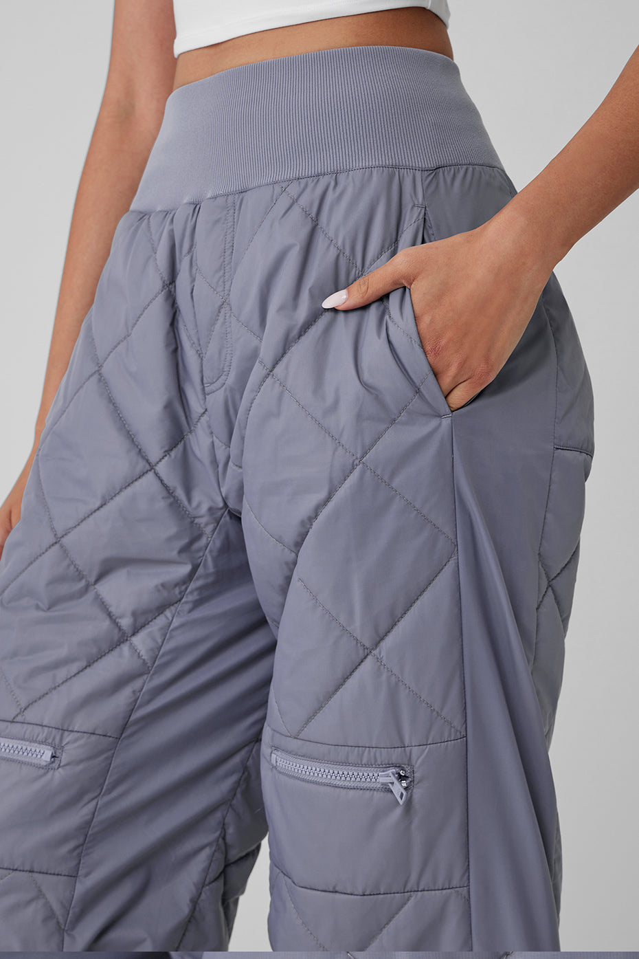 Close-up of high-waist Snowrider puffer pant showcasing quilted finish and zippered pockets.