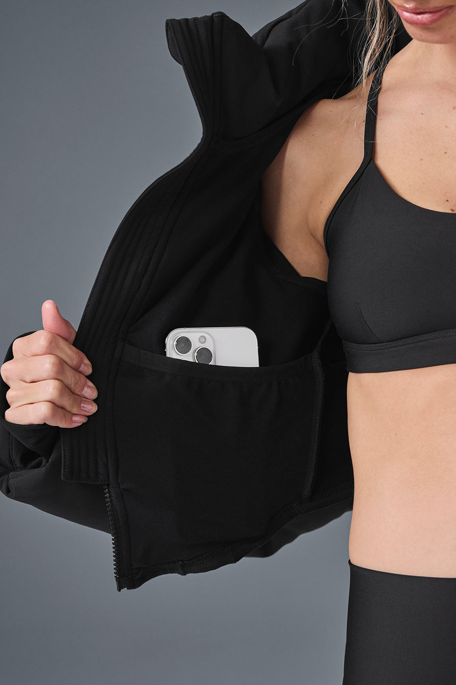 Inside view of a black puffer jacket showing a phone pocket, highlighting its functional design and cropped silhouette.