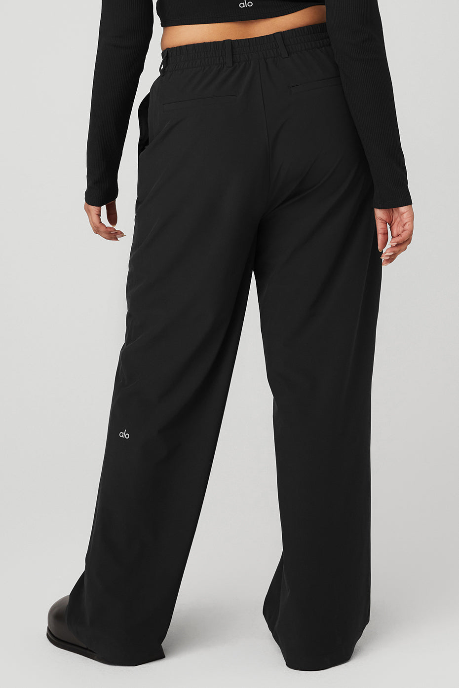 Back view of High-Waist Pursuit Trousers featuring a relaxed wide-leg fit and stretchy waistband in black fabric.