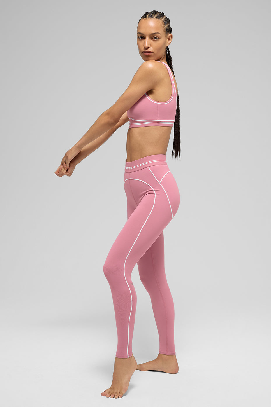 Model wearing Airbrush High-Waist Heart Throb Legging in pink with matching bra, showcasing contouring contrast stitching.