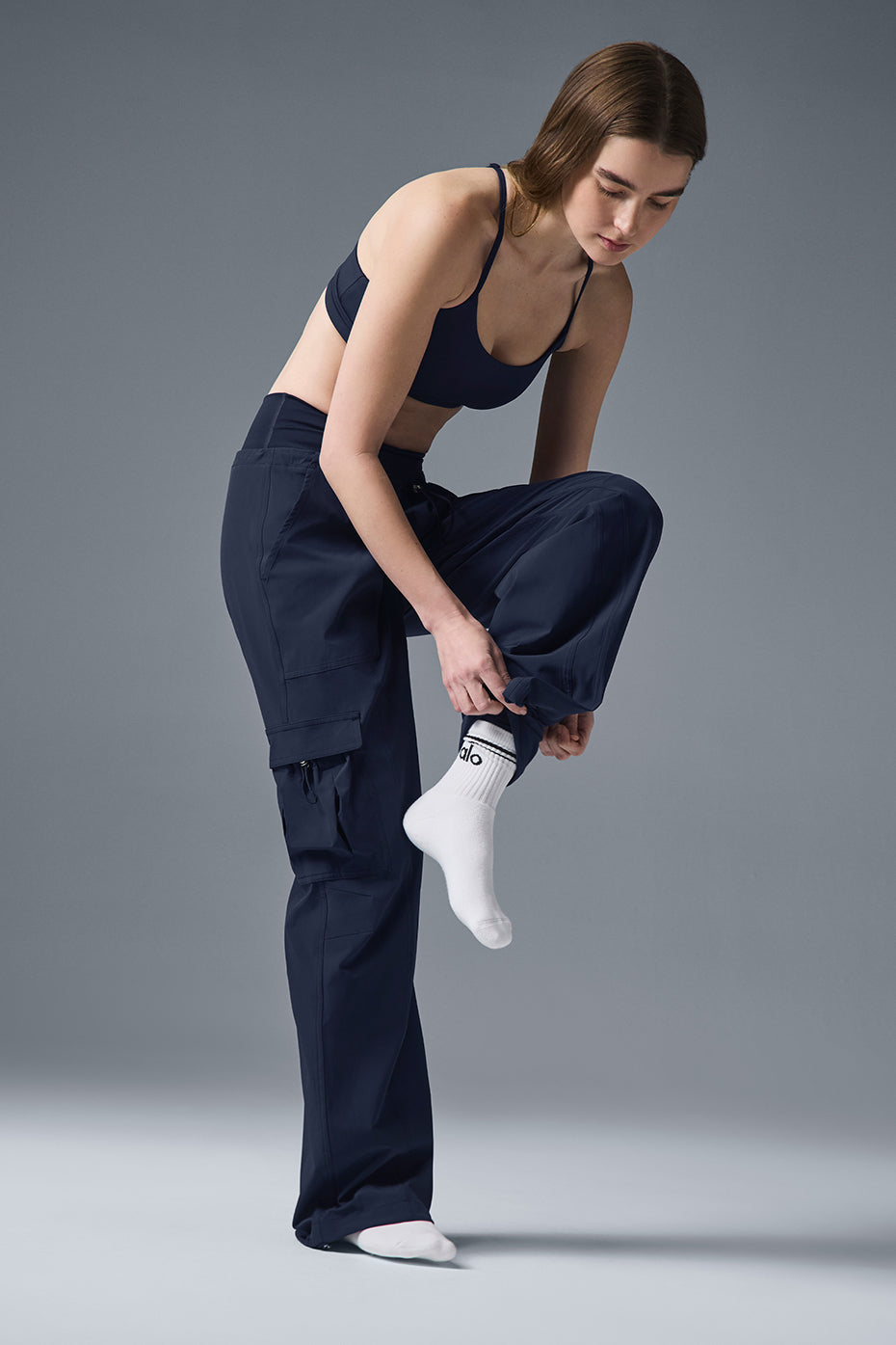Model wearing Megastar Cargo Pant with straight legs and adjustable bungee hems, pairing with a cropped tank top.