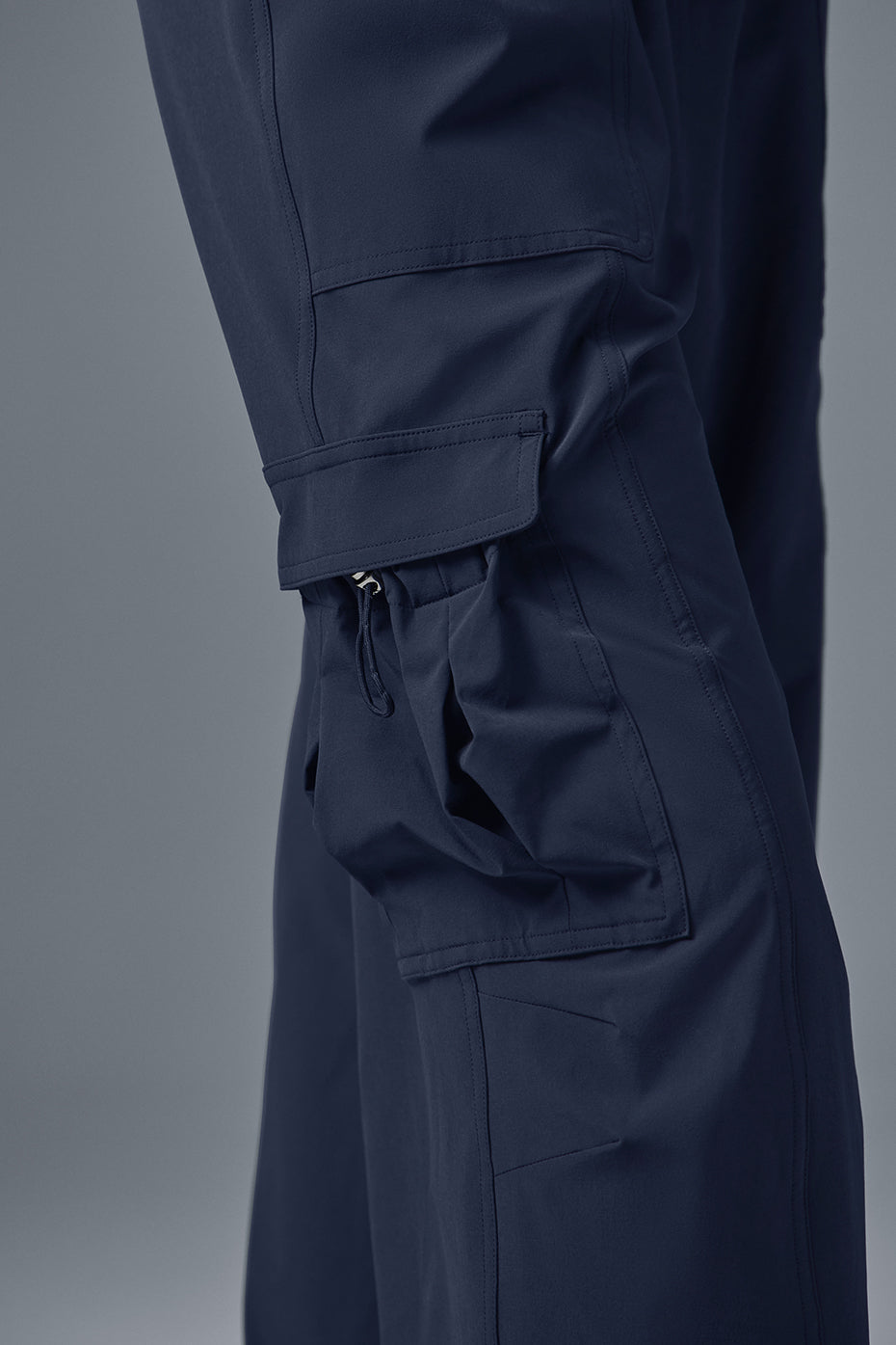 Megastar Cargo Pant close-up showing adjustable bungee hems and pockets in dark blue performance fabric.