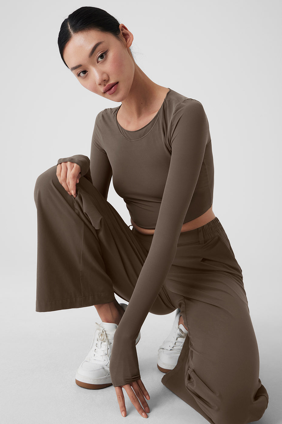 Model wearing a brown cropped top and high-waist wide-leg trousers, showcasing a stylish and comfortable outfit.