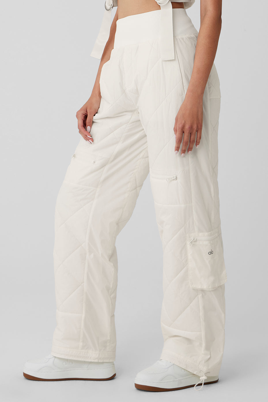 High-waist puffer pant in white with quilted finish, ribbed waistband, and pockets for stylish winter wear.