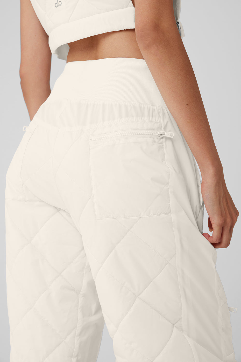 Rear view of a model wearing High-Waist Snowrider Puffer Pant with a quilted finish and wide ribbed waistband.