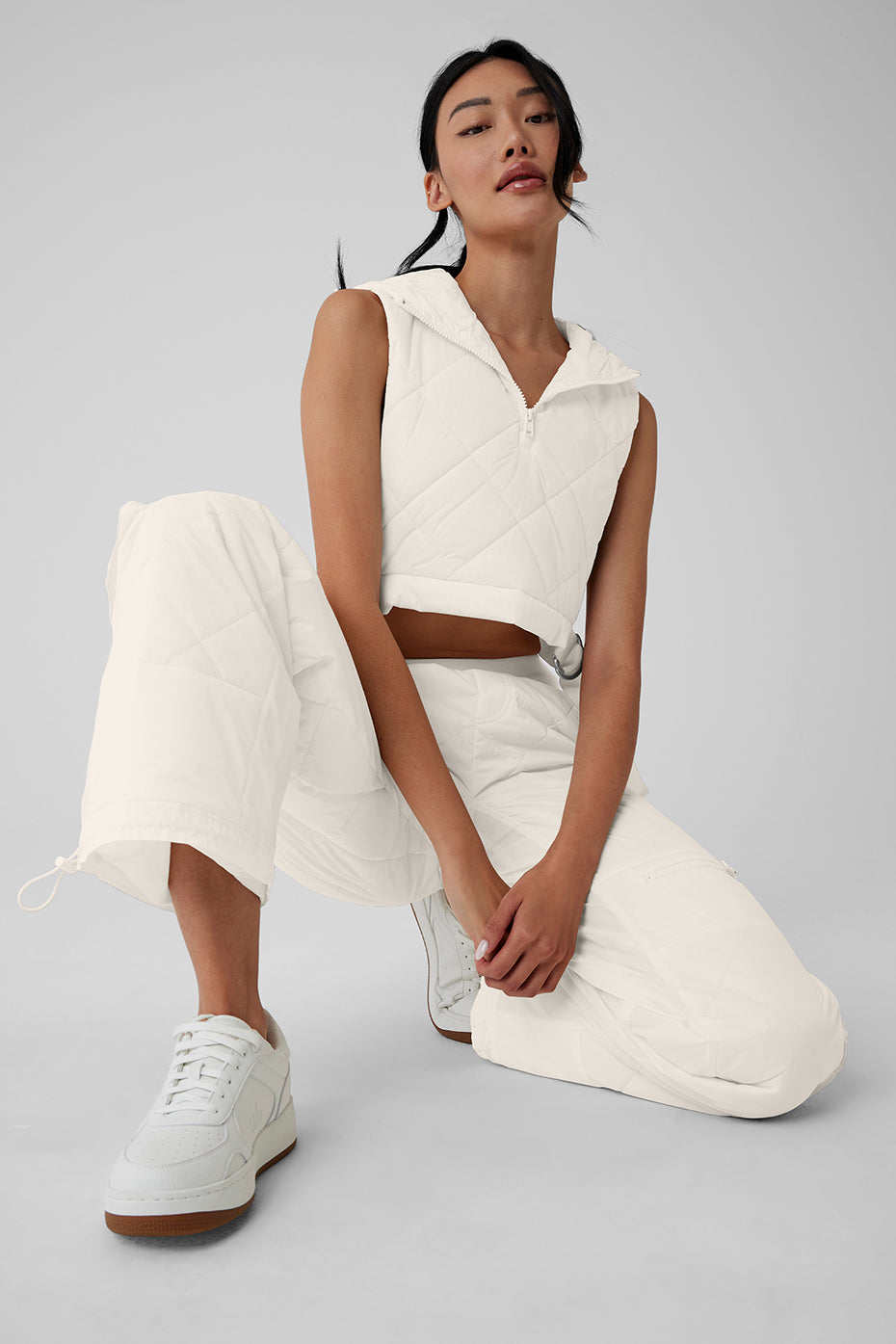 Model wearing High-Waist Snowrider Puffer Pant with quilted finish and hooded crop top in white.