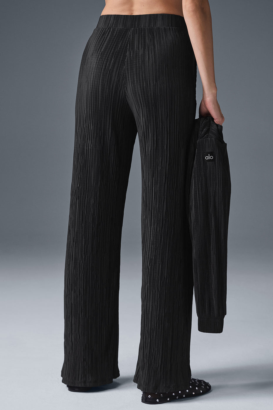 High-waist micro plisse straight leg pant with relaxed fit, soft textured fabric, puddling at the ankle, view from the back.