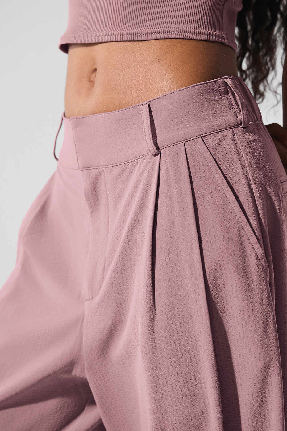 Close-up of High-Waist Dreamscape Trouser showcasing pleats and crinkle fabric in a soft pink color.
