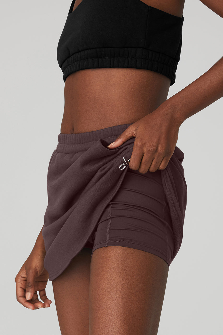 Model showcasing the High-Waist Accolade Skirt with internal shorts and side pockets in a stylish pose.