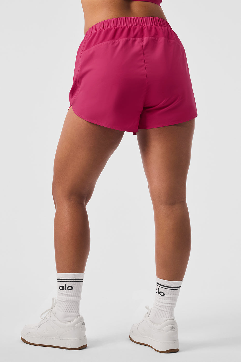 Back view of Playmaker Dolphin Shorts, showcasing sporty design and elastic waistband in vibrant pink color.