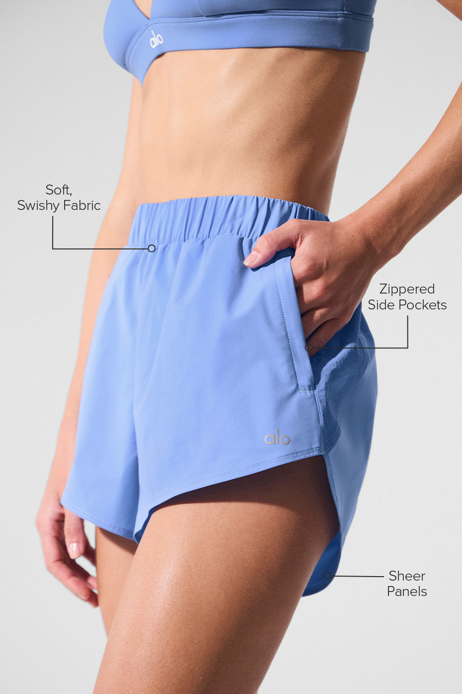 Playmaker Dolphin Short in light blue showcasing soft swishy fabric, zippered side pockets, and sheer panels.