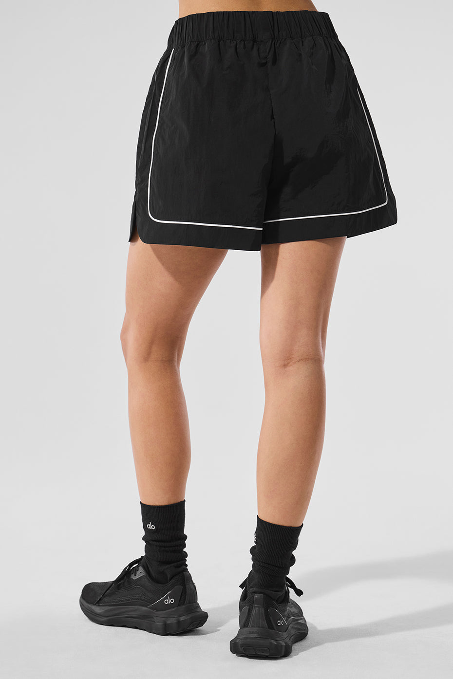 Back view of Motivate Track Short featuring contrast piping, zippered pockets, and sporty design.