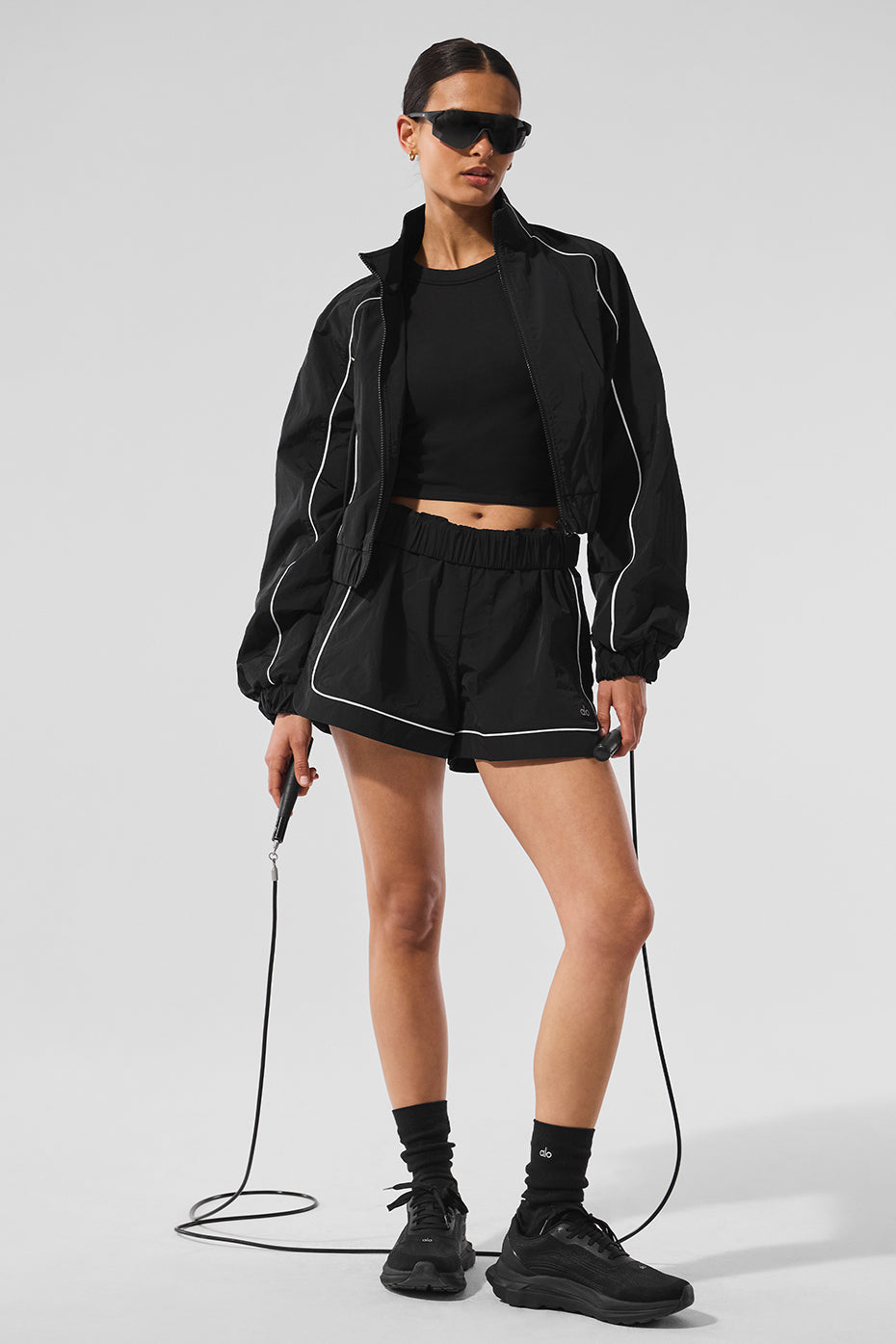Model wearing Motivate Track Short with contrast piping and zippered pockets, styled for sporty chic look.