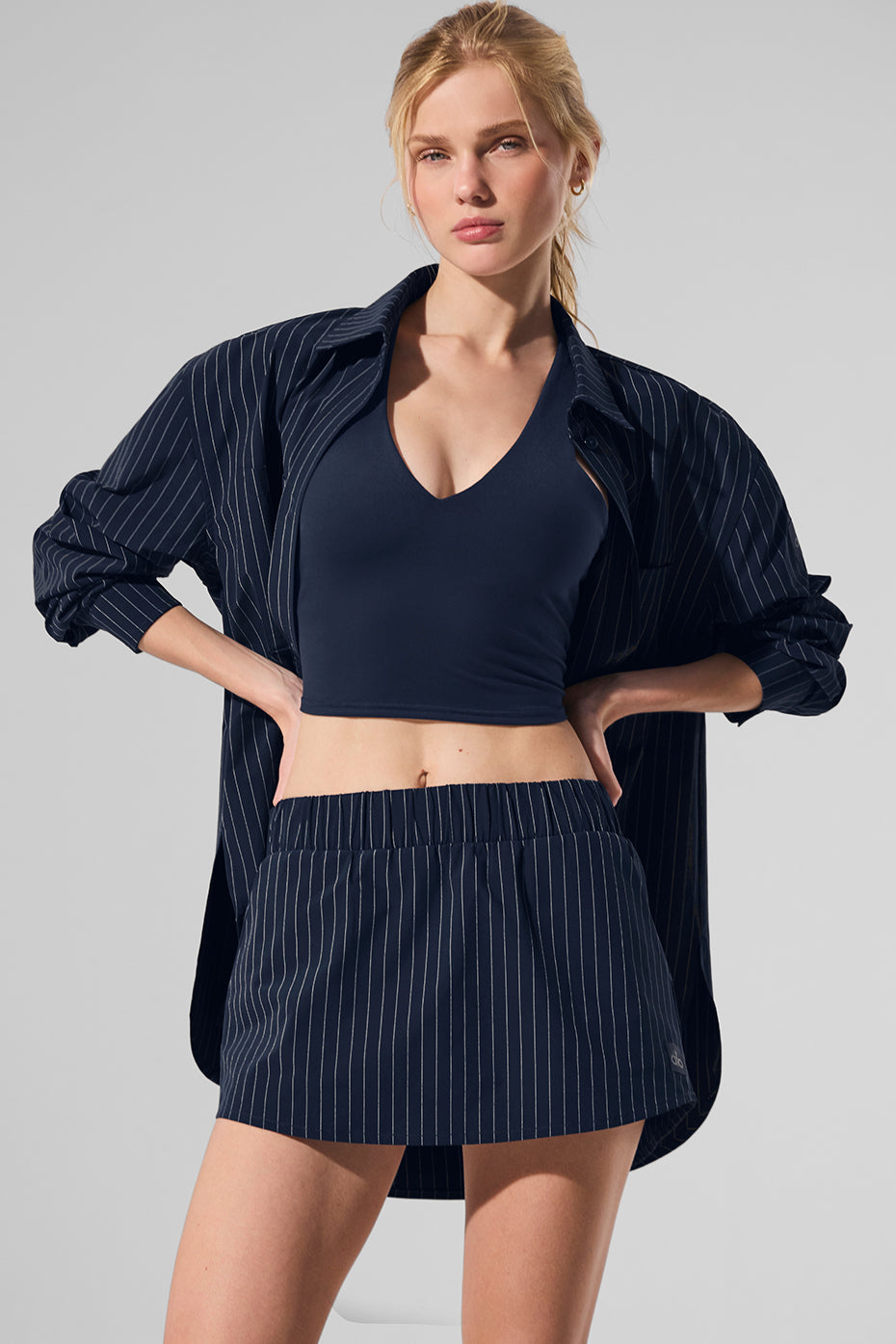 Model wearing the Pinstripe Daylight Mini Skirt with matching button-down, perfect for sunny days and late nights.