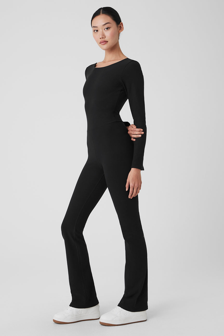 Model wearing Alosoft Melody Full Length Bootcut Onesie in black, showcasing boat neck and bell sleeves.
