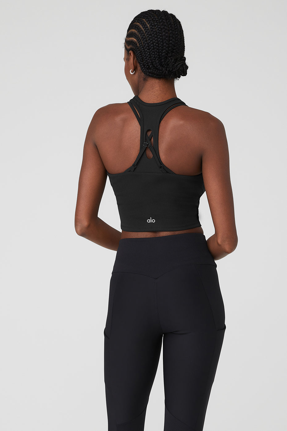 Back view of a woman wearing a Ribbed Airlift Enchanted Bra Tank and high-waist performance leggings.