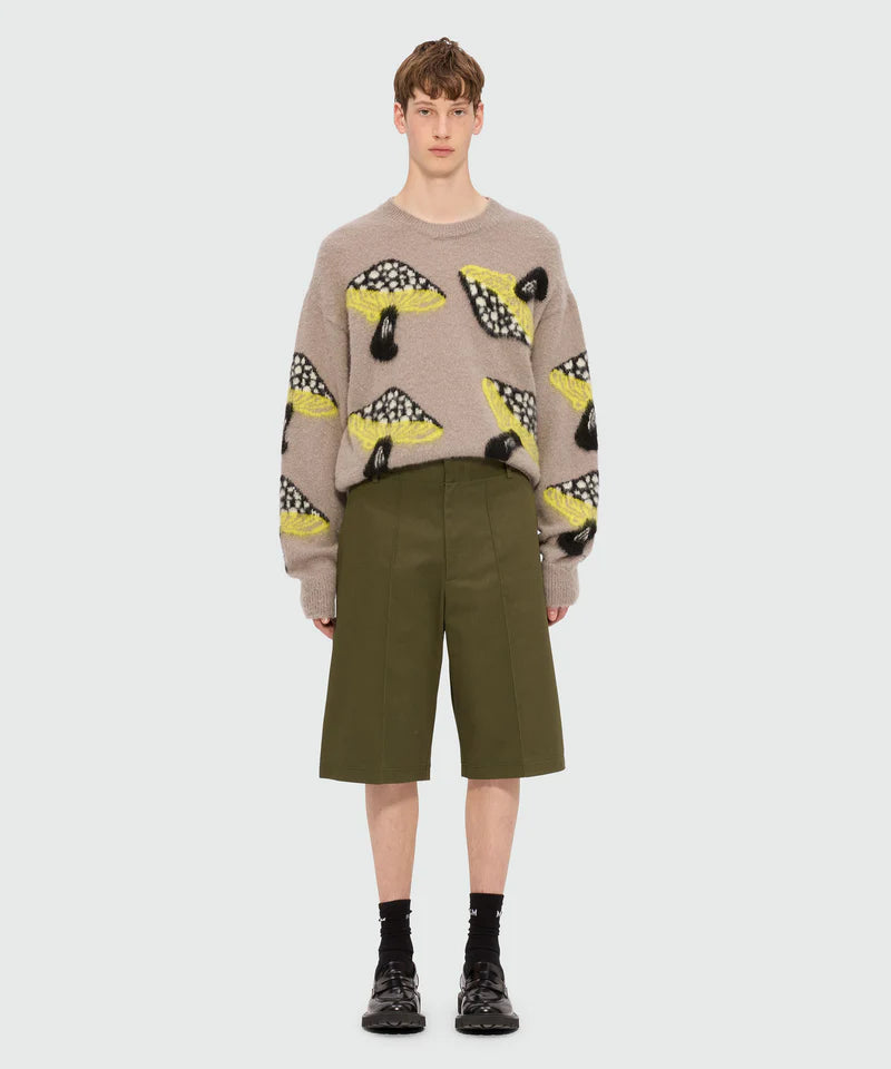 Model wearing olive green Bermuda shorts in cotton drill with pleats and embroidered MSGM logo.