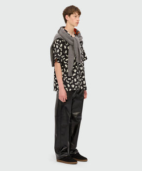 Model wearing a black poplin bowling shirt with 'Follow the Rabbit®' print and relaxed pants.