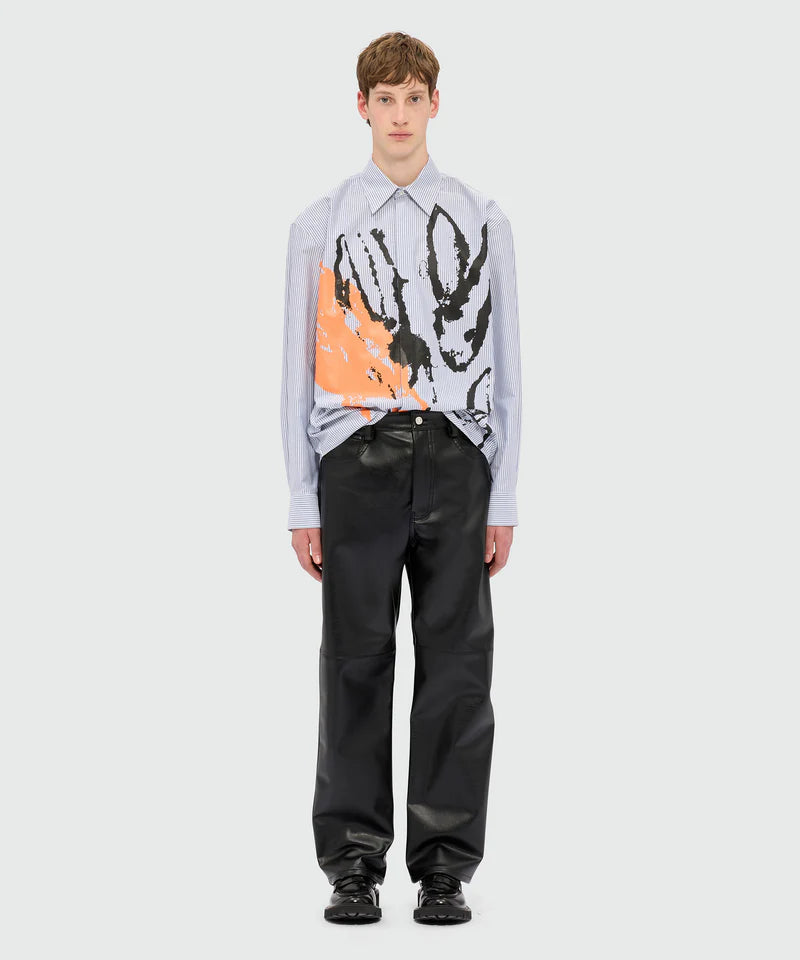 Model wearing structured black textured faux leather trousers with oversized fit and graphic shirt.