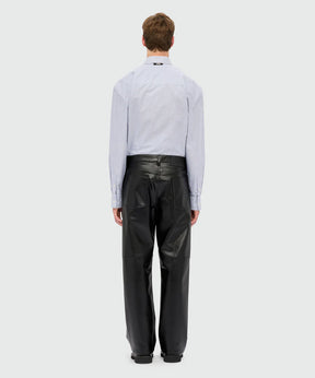 Model wearing black textured faux leather trousers with oversized fit, five-pocket styling, and MSGM logo patch.