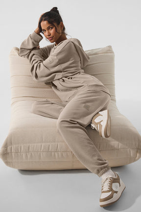 Woman in Chill Vintage Wash Hoodie and sweatpants relaxing on a large cushion, showcasing casual vintage style and comfort.