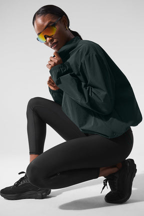 Model wearing Light Weight Takeaway Track Pullover with quarter-zip, relaxed fit, and zippered pockets, styled with leggings.