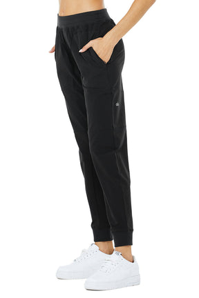 Model wearing sleek black Co-Op Pants with elastic waistband and side-zip pockets, ideal for active lifestyles.