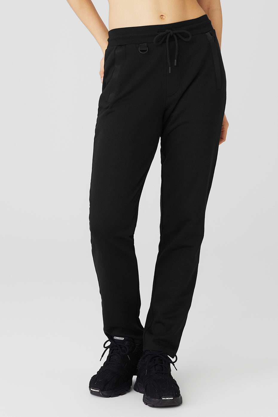 Nomadic Sweatpant in black, featuring zippered front pockets and D-ring, perfect for workouts or casual outings.