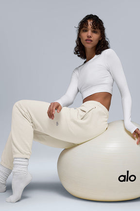 Model wearing Chill Sweatpant and fitted top, seated on exercise ball showcasing stylish comfort and breathability.