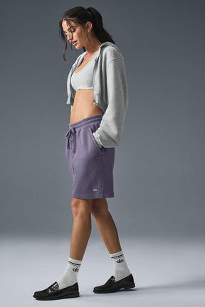Woman wearing purple Chill Shorts made of French terry with drawstring and side-zip pockets, styled casually.