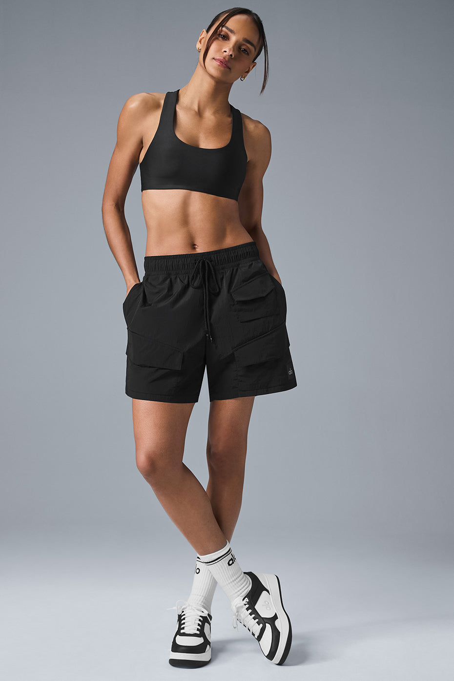 Model wearing 7" Crinkle Nylon Excursion Cargo Shorts in black with drawstring waist and cargo pockets