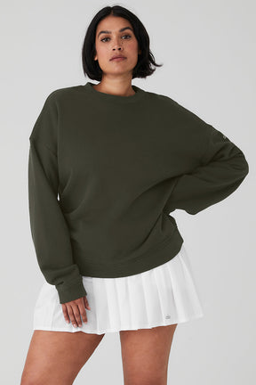 Woman wearing Renown Heavy Weight Crew Neck Pullover in green with oversized fit paired with a white pleated skirt.