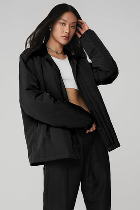 Model wearing the Legend Jacket, a lightweight black puffer with sleek design, front zipper, and snap closure.