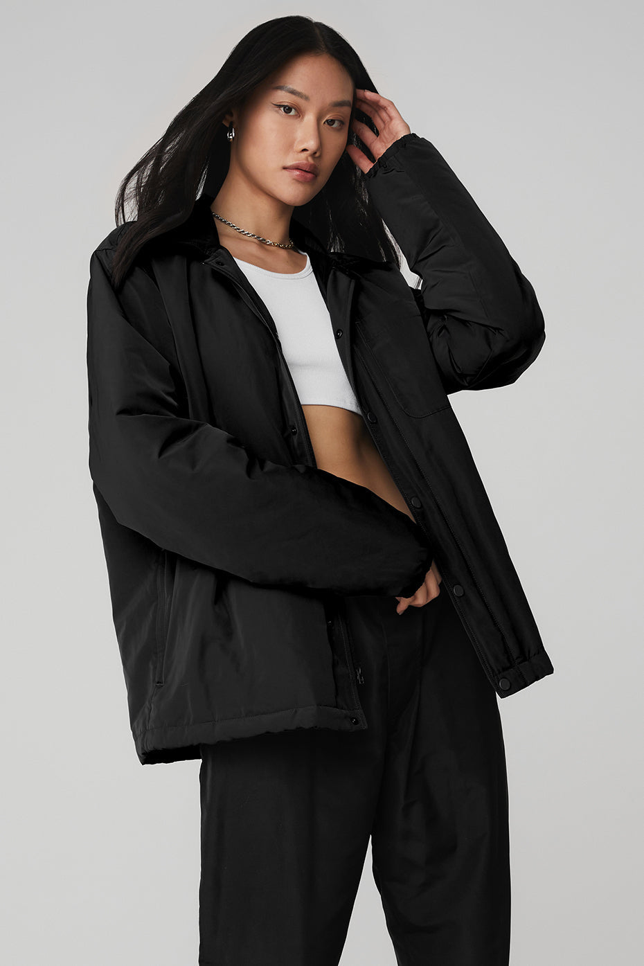 Model wearing the Legend Jacket, a lightweight black puffer with sleek design, front zipper, and snap closure.