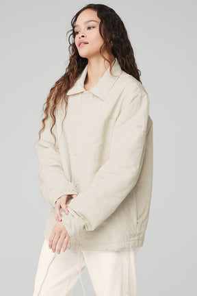 Model wearing the Legend Jacket in beige, featuring a relaxed fit, iconic collar, and stylish front pockets.