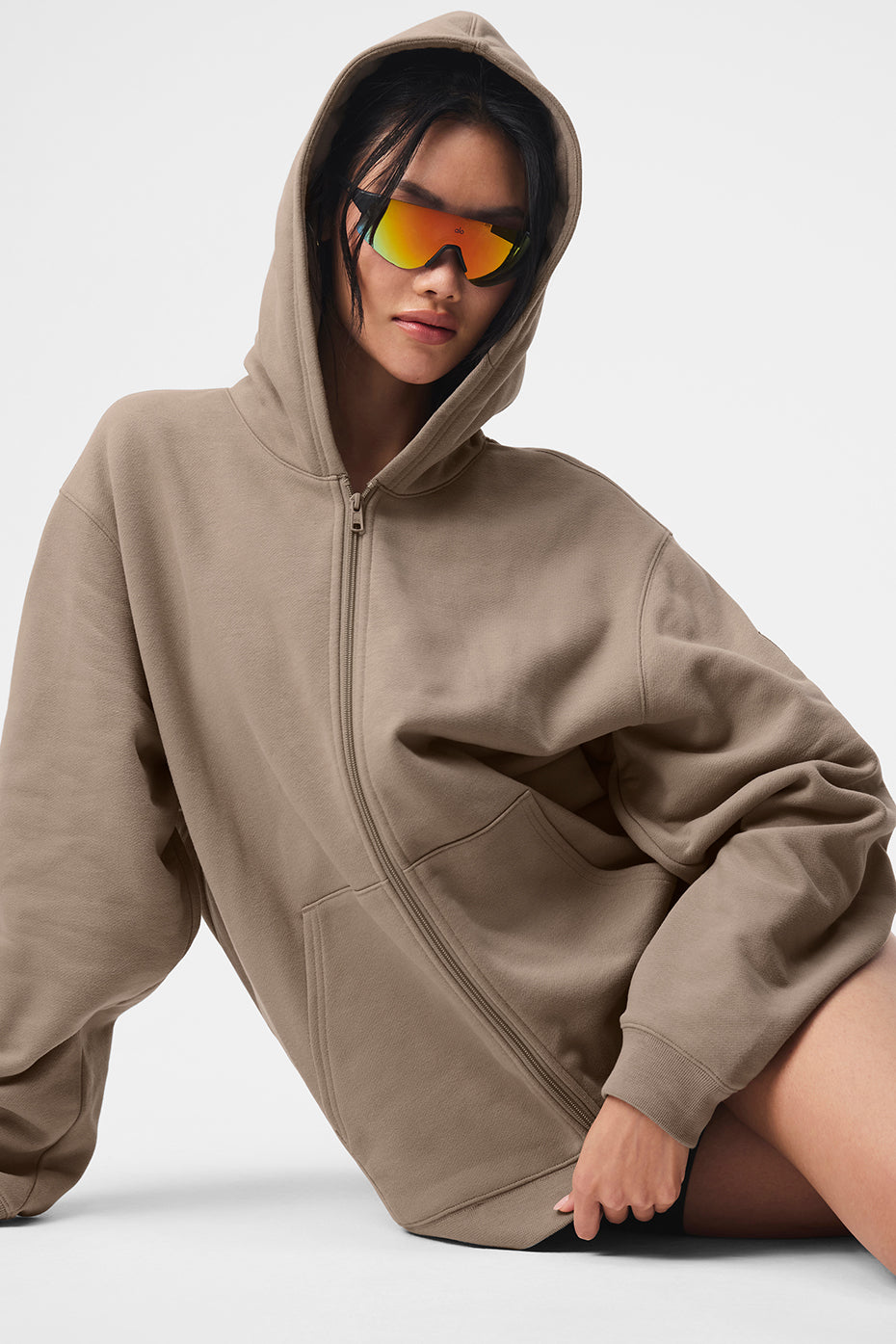 Model wearing Renown Full Zip Hoodie in beige with sunglasses, showcasing oversized fit and relaxed style.