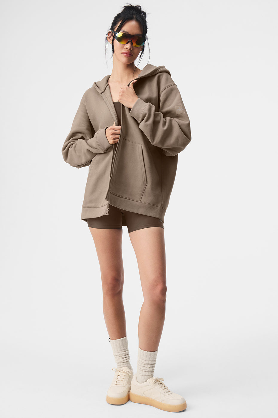 Model wearing a Renown Full Zip Hoodie in beige, showcasing oversized fit with dropped shoulders and stylish athleisure look.