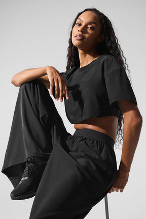 Model wearing a Mesh Cropped Mirage Tee with relaxed fit and longer sleeves, paired with chic black pants.