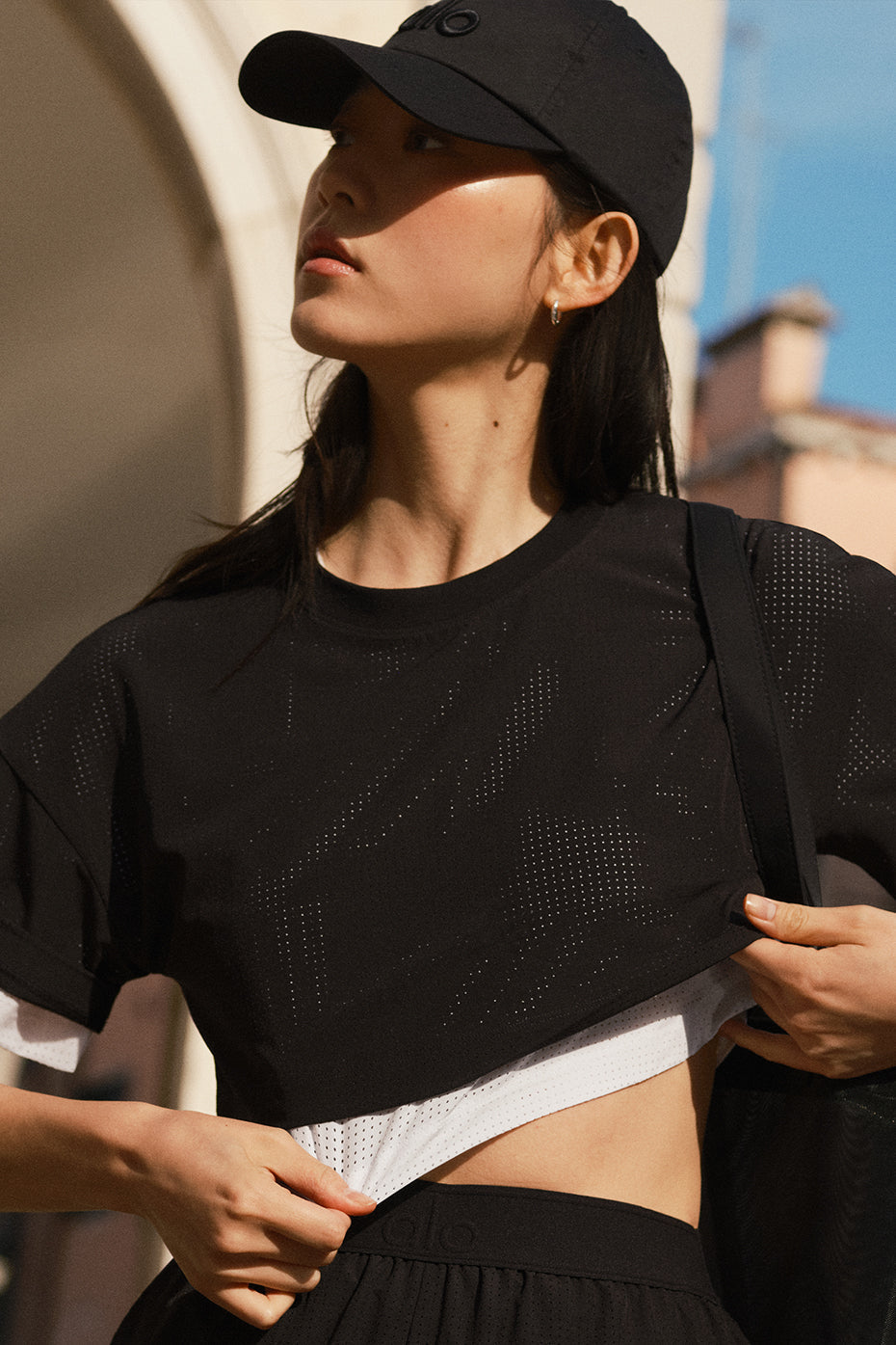Model wearing a Mesh Cropped Mirage Tee in black, showcasing its lightweight and breathable fabric.