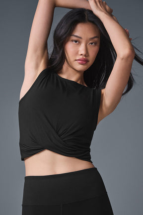 Model wearing a fitted black Cover Tank with front wrap detail and raw edge finish, showcasing soft jersey fabric.
