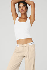 Model showcasing the Seamless Chosen Tank in white with high-waisted beige pants, highlighting its fitted silhouette and scoop neckline.