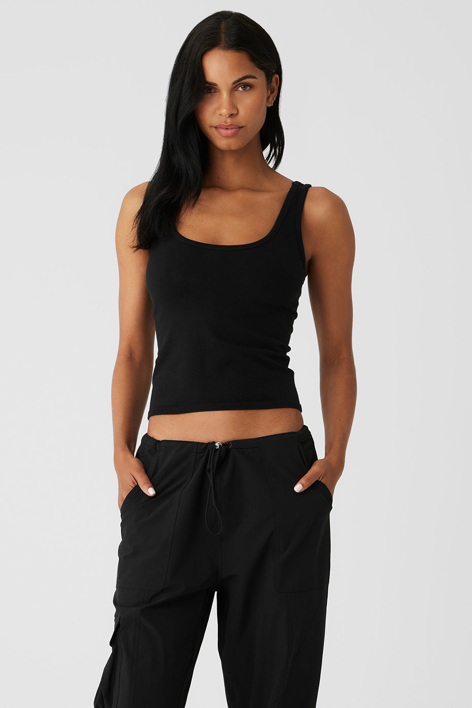 Model wearing the Seamless Chosen Tank, a lightweight black ribbed tank top, styled with relaxed pants.