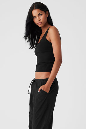Model wearing a black seamless chosen tank top with a fitted silhouette and scoop neckline, paired with casual black pants.