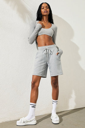 Model wearing a ribbed defined long sleeve bra with gray shorts, showcasing a stylish and comfy athleisure look.