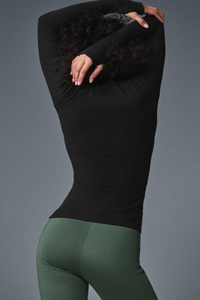 Woman wearing a Wellness Rib Mock Neck Long Sleeve top paired with high-waist leggings, showcasing a sleek and comfortable look.