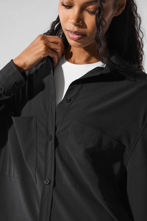 Model wearing the Dreamscape Button Down Long Sleeve in black, featuring front pockets and a lightweight crinkle woven fabric.